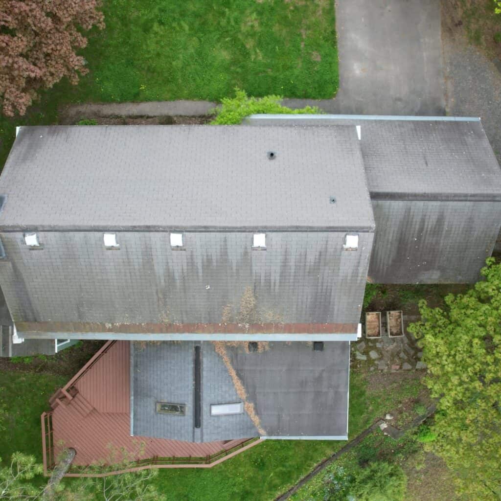 Aerial view of a residential property with roof and yard.