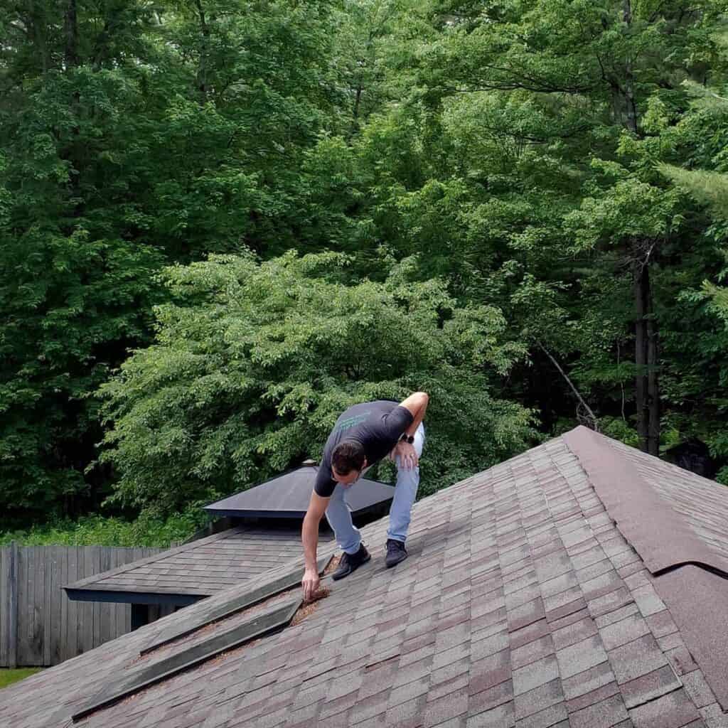 Home inspector examining asphalt roof shingles during a roof inspection